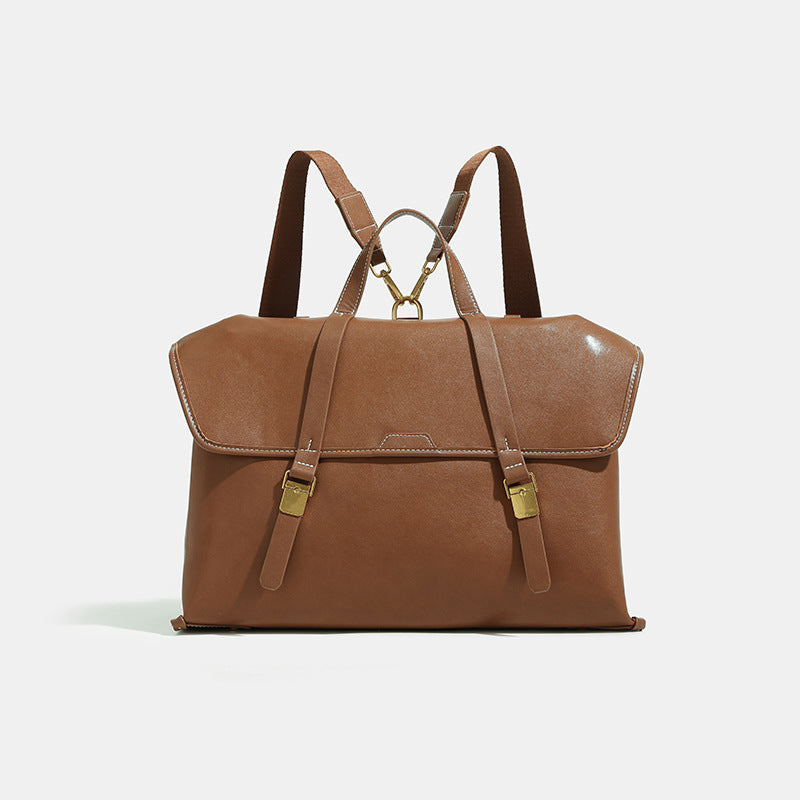 Structured flap-over backpack satchel in smooth leather-look finish with gold-tone buckle hardware and top handle, detail
