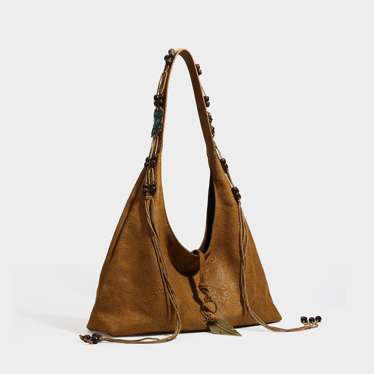 Slouchy boho hobo shoulder bag in embossed brown suede-look finish with beaded strap, cord tassels, and brass-tone leaf