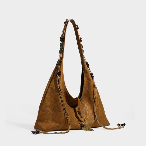 Slouchy boho hobo shoulder bag in embossed brown suede-look finish with beaded strap, cord tassels, and brass-tone leaf