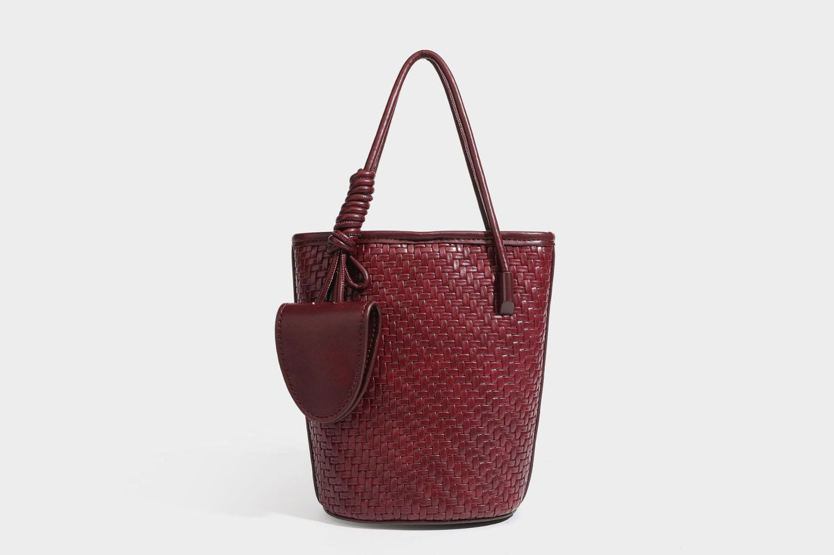 Structured woven-texture leather-look bucket bag in brown with knotted top handles, small front flap pouch, and adjustable