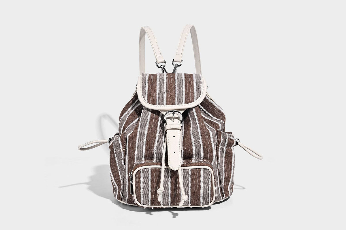 Weicher Rucksack aus gewebtem Material mit vertikalen Streifen, Überschlag, Kordelzug, vorderer Reißverschlusstasche, weißen Besätzen und Trägern in Lederoptik, Detailansicht