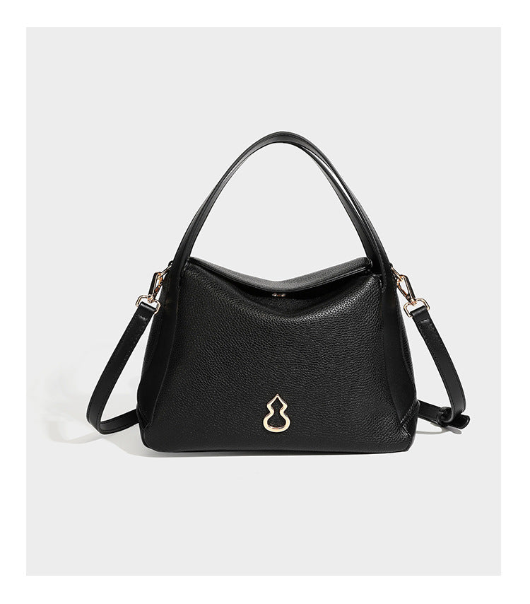 Structured pebbled leather-look shoulder bag with flap top, gold-tone emblem hardware, dual top handles, and detachable