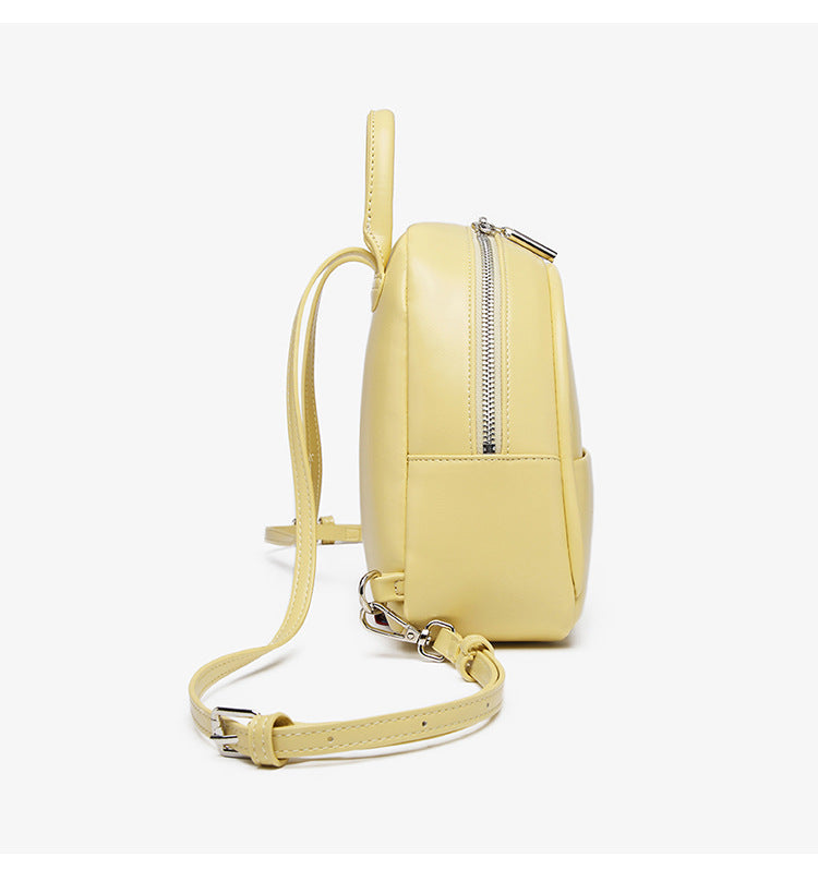 Kleine kuppelförmige Mini-Rucksackhandtasche in Pastellgelb mit glatter Lederoptik, oberem Bogenreißverschluss und silberfarbenen Details, Detailansicht