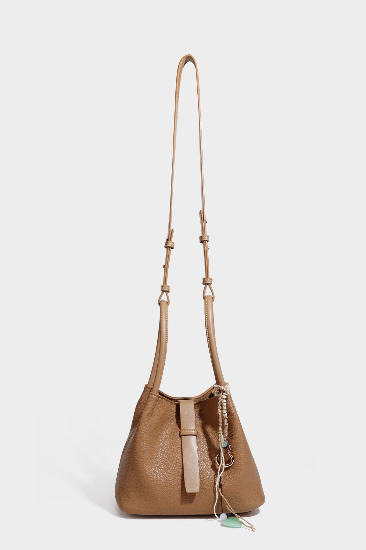 Pebbled leather-look bucket tote bag with rolled double handles, drawstring closure, braided cord charm, and detachable