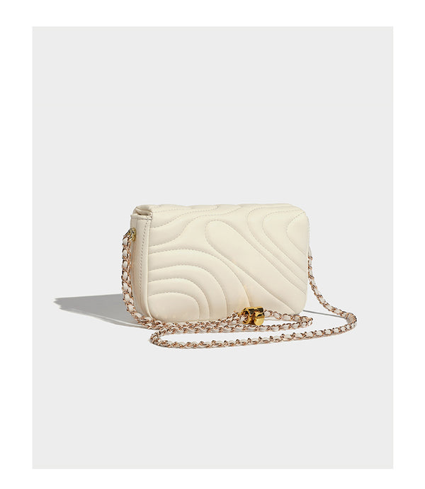 Compact cream quilted flap crossbody bag with wave stitching, gold-tone chain strap, and four-petal turn-lock clasp, detail
