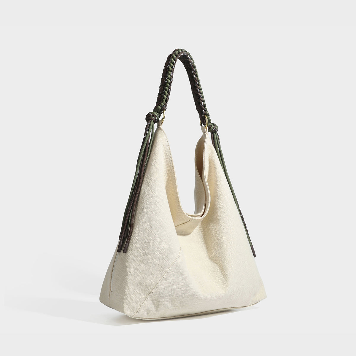 Soft slouchy cream canvas shoulder tote with braided brown and green cord handle, gold-tone ring hardware, and tassel trim