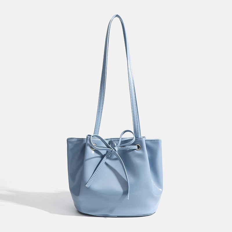 Soft glossy leather-look bucket bag with bow drawstring closure and silver-tone grommets, front view