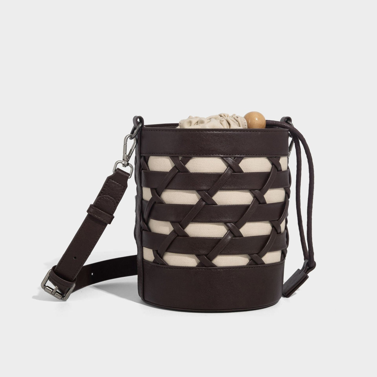 Small cylindrical woven lattice bucket bag with leather-look black trim, beige canvas body, wooden bead drawstring closure