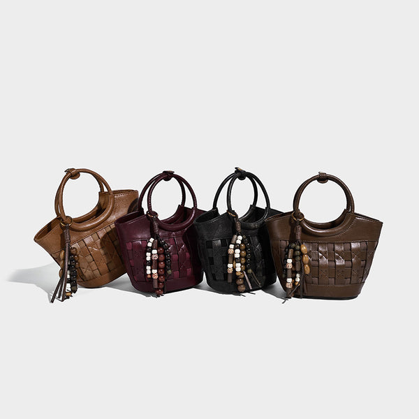 Small woven-panel bucket bag with circular ring handles, beaded tassel charm, and detachable crossbody strap in brown, detail