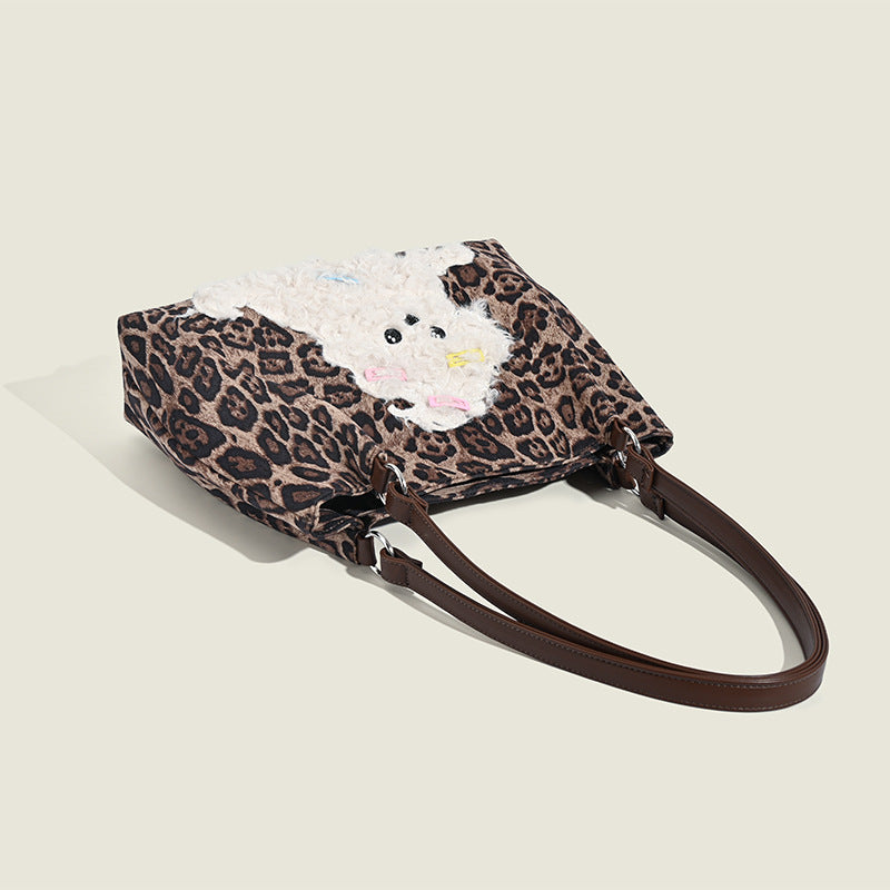 Leopard-print fabric tote bag with white plush teddy bear appliqué and brown leather-look shoulder straps, detail view 3