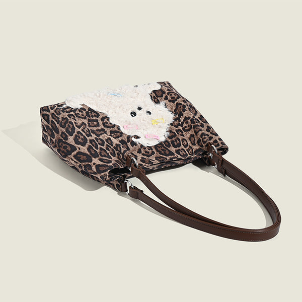 Leopard-print fabric tote bag with white plush teddy bear appliqué and brown leather-look shoulder straps, detail view 3