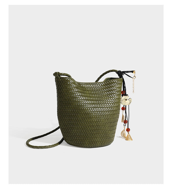 Olive green woven leather-look bucket bag with braided crossbody strap, knotted adjustment, and gold-tone tassel charm with