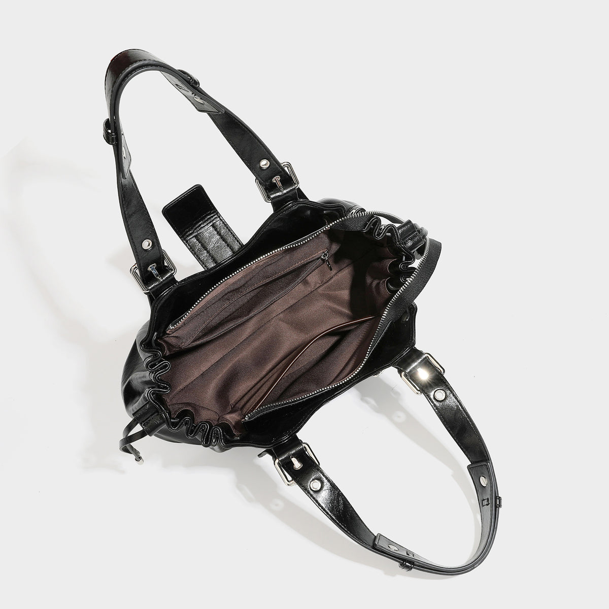 Large black glossy leather-look tote bag with silver buckle straps, eyelet grommet panels, drawstring side gathers, and