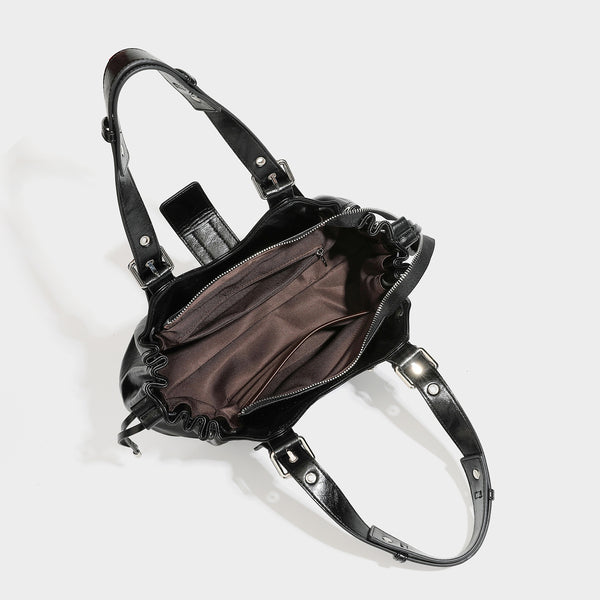 Large black glossy leather-look tote bag with silver buckle straps, eyelet grommet panels, drawstring side gathers, and