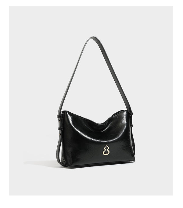 Lässige Hobo-Schultertasche mit offenem oberen Abschluss in glänzender karamellfarbener Lederoptik mit goldfarbenen Logo-Beschlägen und langem, verstellbarem