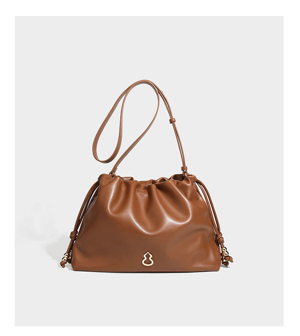 Slouchy ruched drawstring shoulder bag in smooth leather-look finish with gold-tone emblem and slim adjustable strap, detail