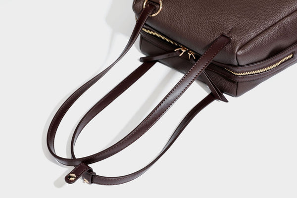 Structured trapezoid shoulder bag in dark brown pebbled leather-look finish with slim double straps, top zip closure, side