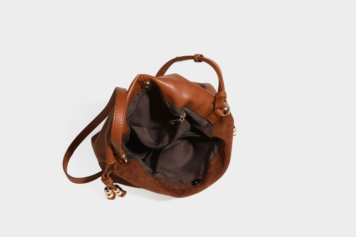 Suede-look drawstring shoulder bag in brown with smooth trim, knotted bead drawstring closure, slim adjustable strap, and