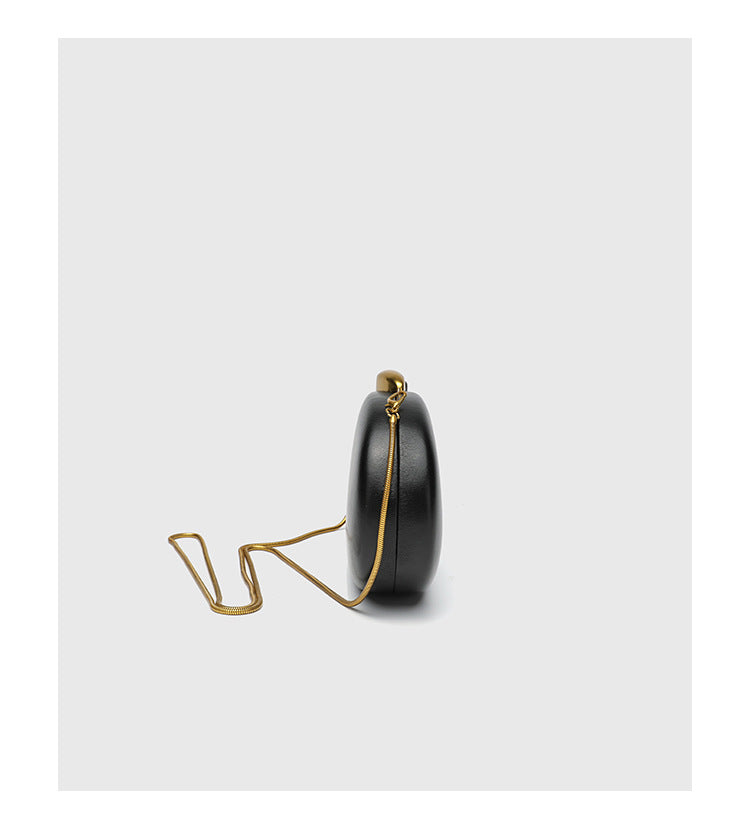 Oval hard-shell crossbody clutch bag with smooth matte leather-look finish and gold-tone snake chain strap, detail view 14