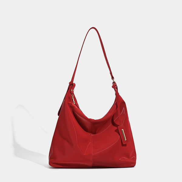 Large red glossy leather-look slouchy hobo shoulder tote bag with zip-top closure and gold-tone hardware, detail view 6