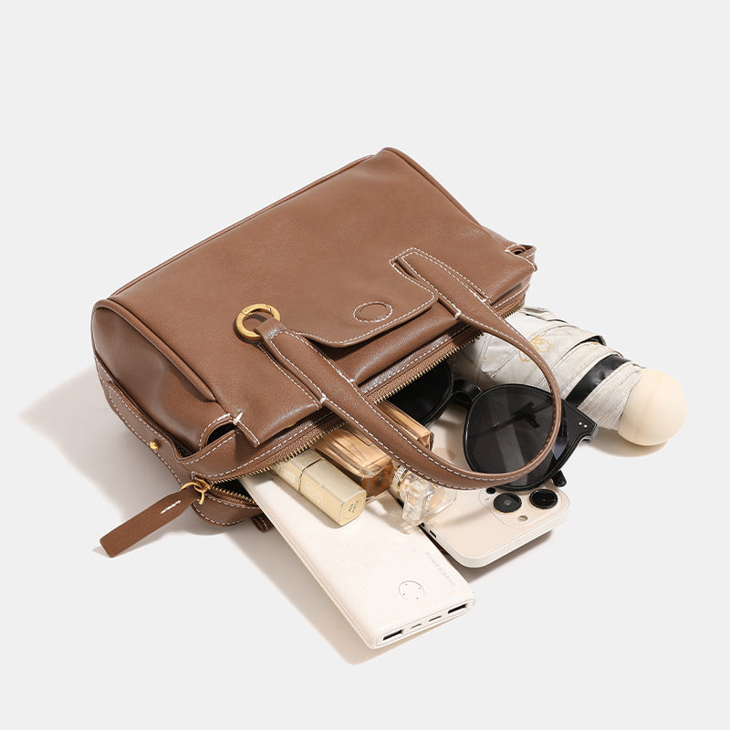 Compact structured satchel bag with dual top handles, gold-tone O-ring hardware, contrast topstitching, and detachable