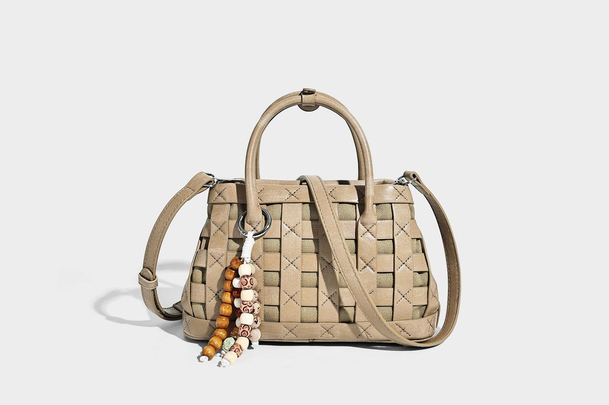 Small structured woven satchel tote with rounded top handles, silver-tone ring hardware, and bead tassel charm, detail view