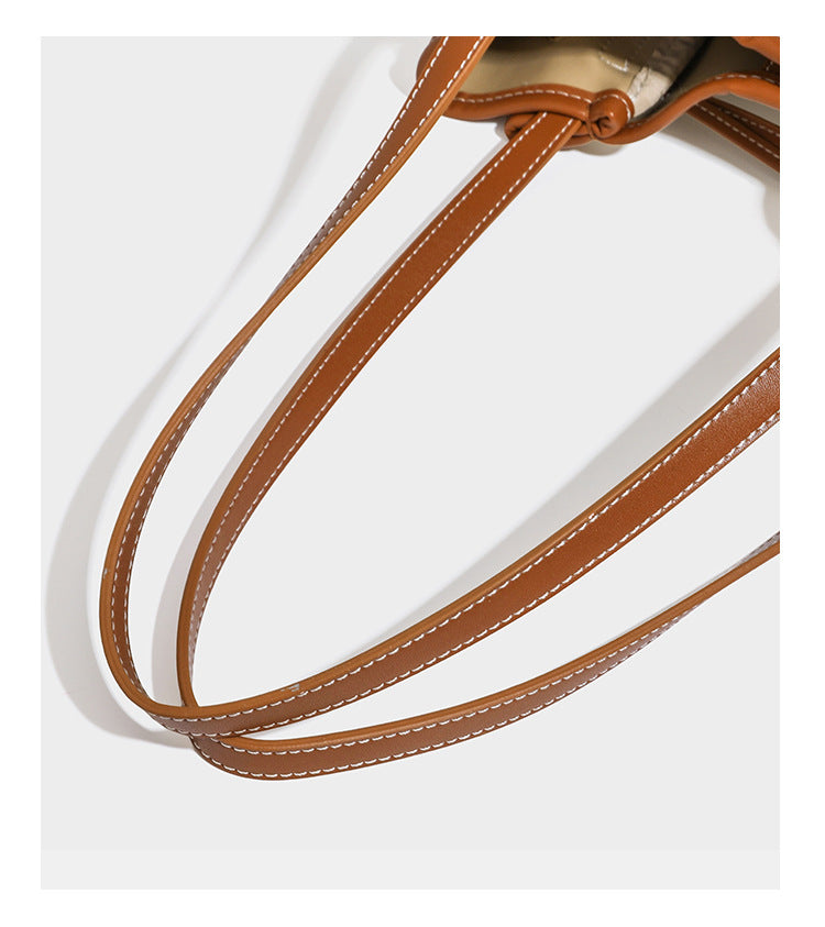 Large cream and navy striped canvas bucket tote bag with tan leather-look trim, drawstring closure, and double shoulder