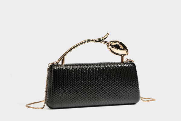 Structured rectangular metallic woven clutch bag with sculptural gold-tone leaf top handle and detachable chain strap, detail