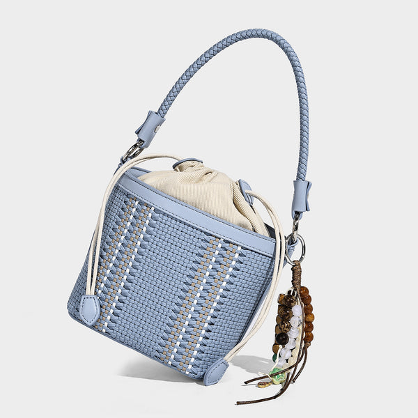 Small woven bucket bag with drawstring top, braided handle, detachable crossbody strap, and silver-tone ring hardware, detail