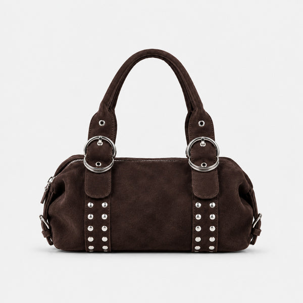 Weiche, matte Schultertasche in Zylinderform aus Veloursleder-Optik mit silberfarbenem Nietenbesatz, Ringschnallen-Details und zwei gerollten Tragegriffen, Detailansicht