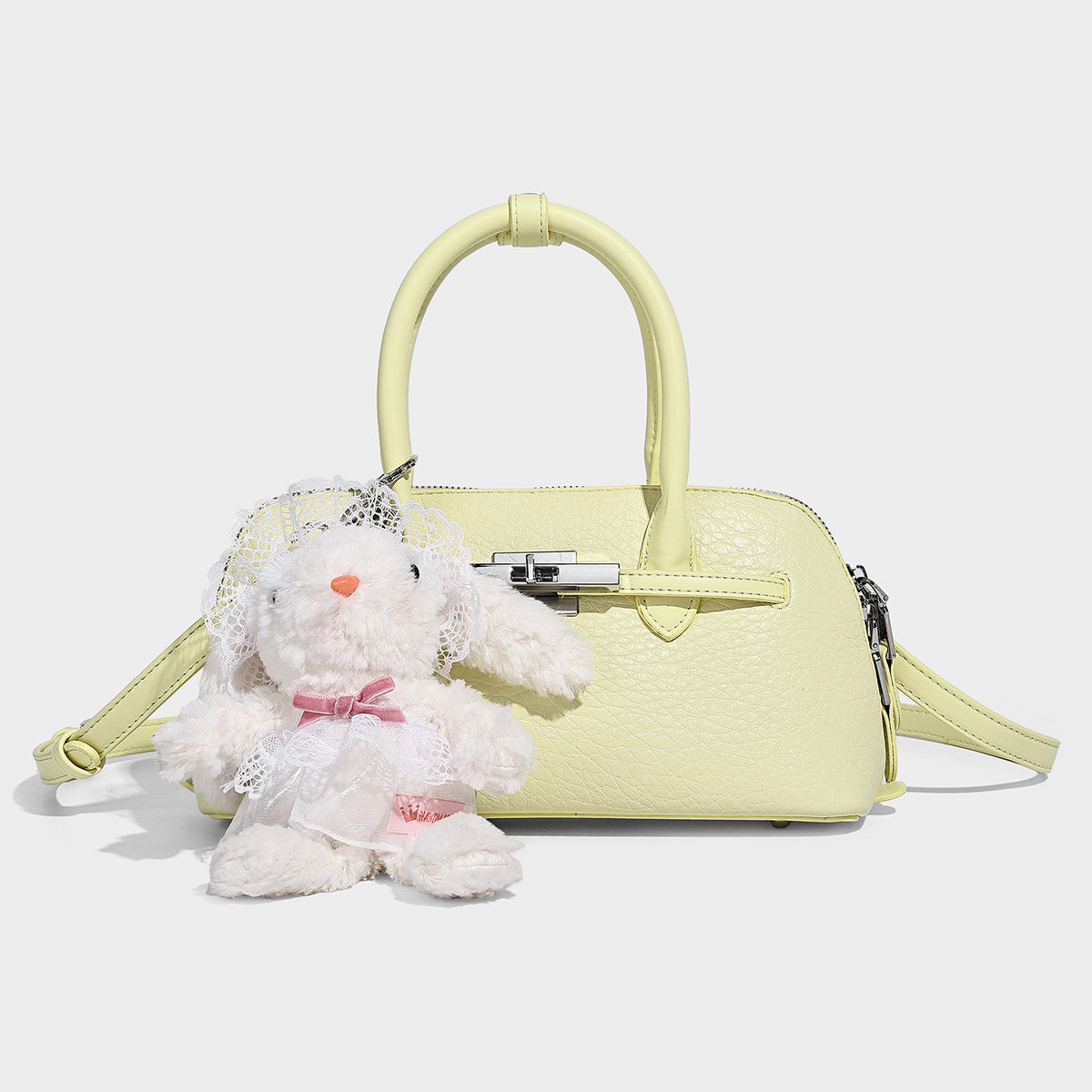 Small structured shell-silhouette top-handle bag with pebbled leather-look finish, silver-tone turn-lock hardware, and