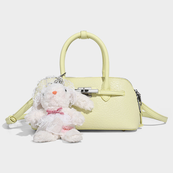 Small structured shell-silhouette top-handle bag with pebbled leather-look finish, silver-tone turn-lock hardware, and