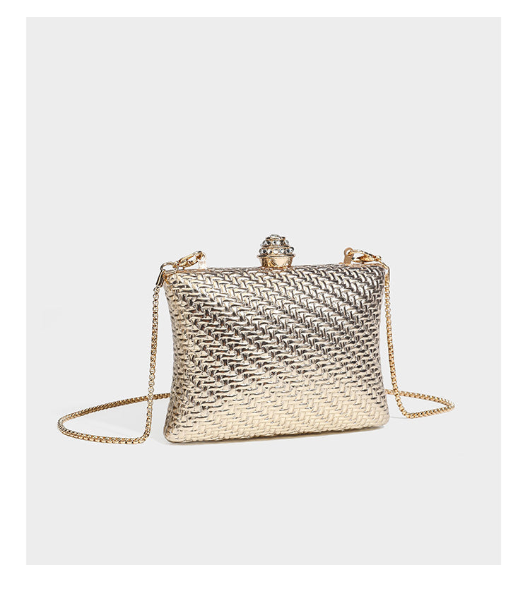 Small structured rectangular metallic woven-texture clutch bag with jeweled knob clasp and gold-tone chain strap, detail view