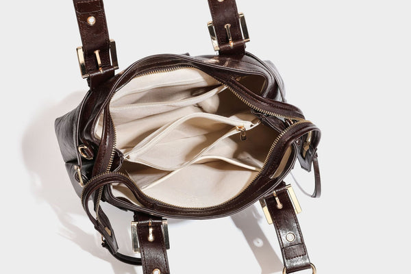 Structured leather-look satchel bag with heart padlock charm, star charm, gold-tone buckle hardware, dual top handles, and