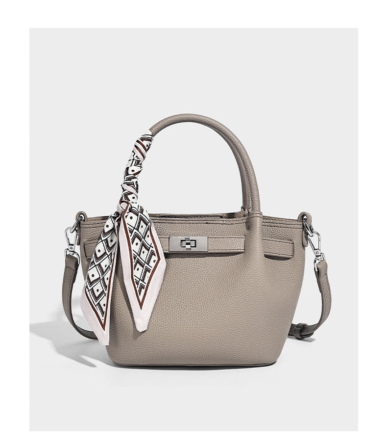 Kleine strukturierte Henkeltasche aus genarbtem Material in Taupe mit zwei Henkeln, bedrucktem Schalband, vorderem Drehverschluss und, Detail