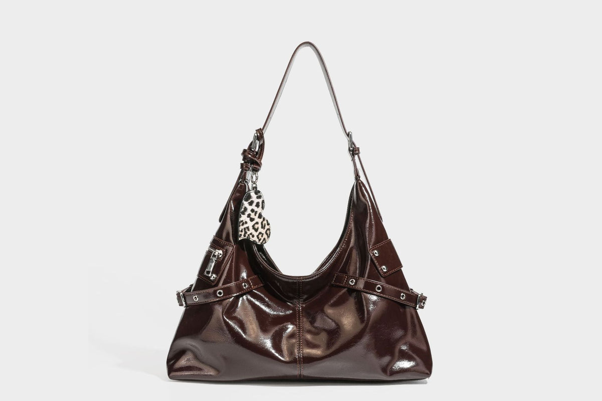 Glänzende dunkelbraune, lässig geschnittene Hobo-Schultertasche mit Riemendetail mit silberfarbenen Ösen, Reißverschlussfach auf der Vorderseite und Herz mit Leopardenmuster