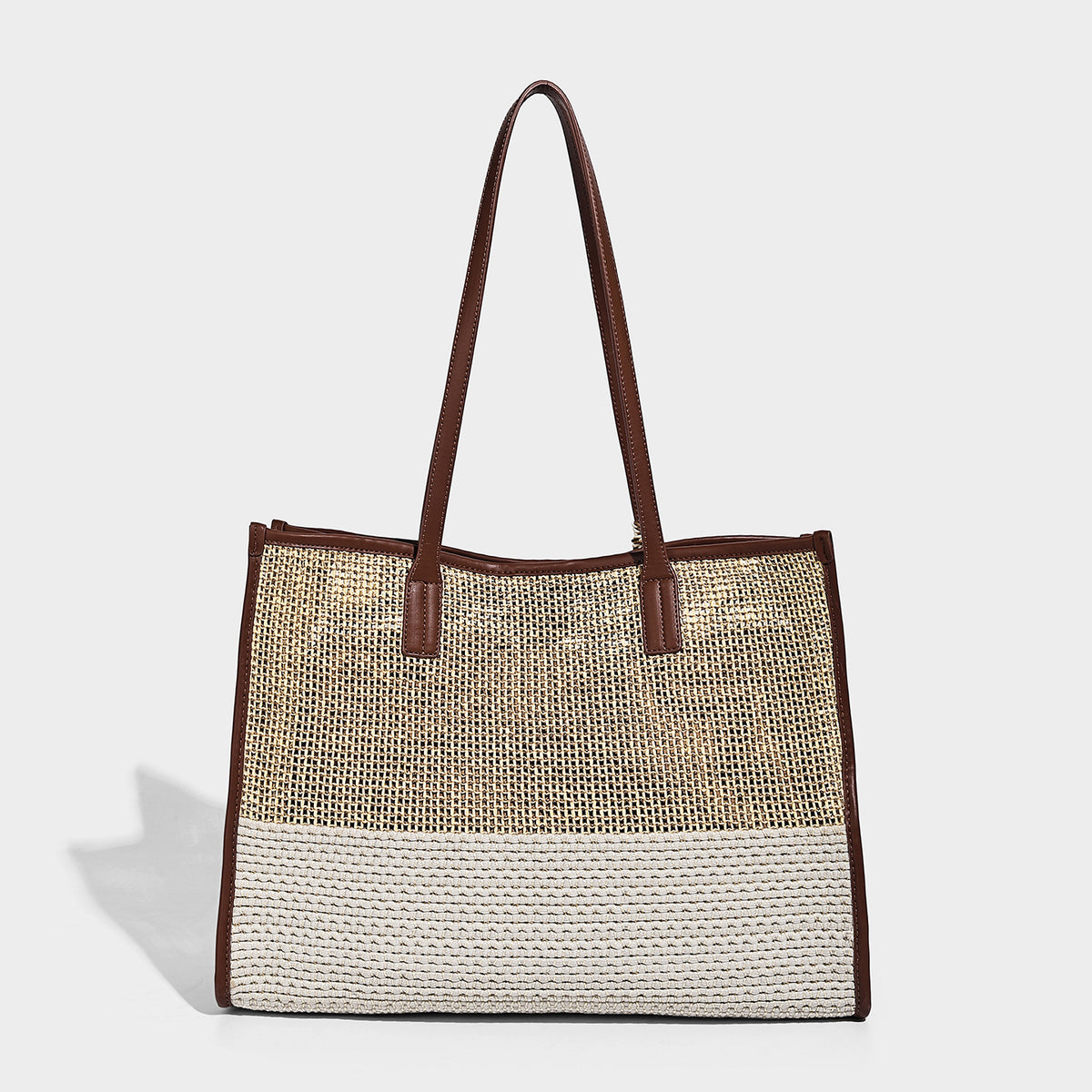Two-tone woven straw tote bag with leather-look brown trim, long shoulder straps, and knotted tassel charm, detail view 4