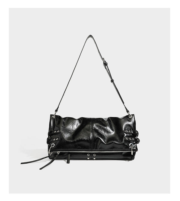 Black glossy leather-look slouchy shoulder bag with silver stud and eyelet hardware, top zip closure, front zip pocket, and