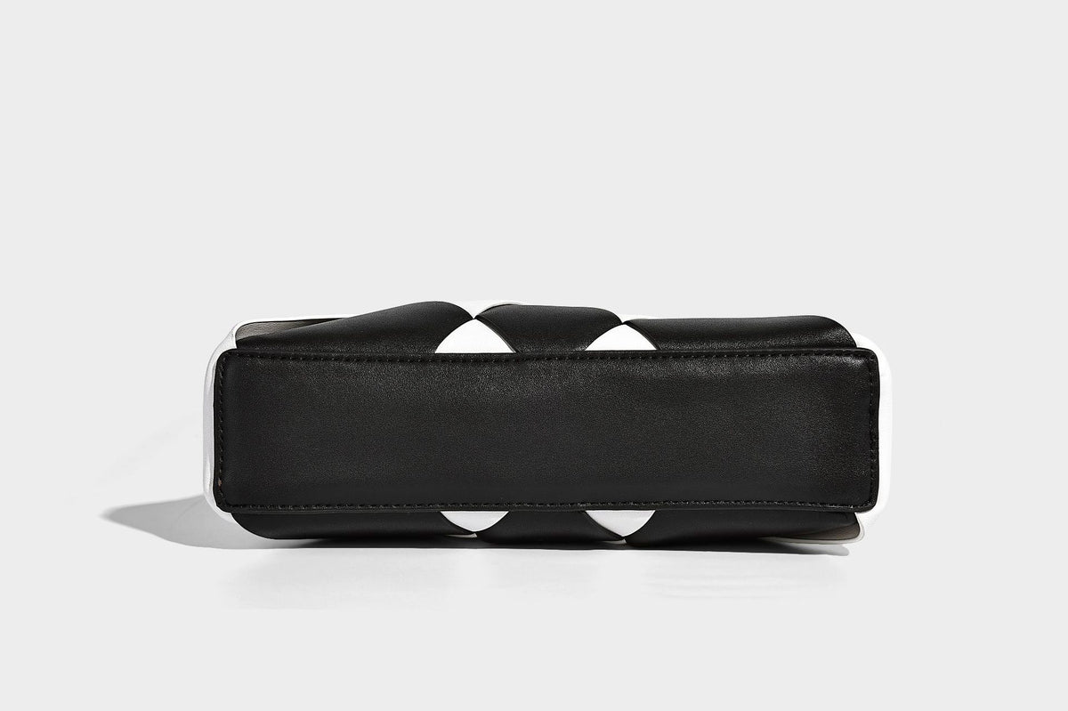 Compact bucket shoulder bag with black-and-white diamond patchwork panels, knotted top handle, gold-tone hardware, and