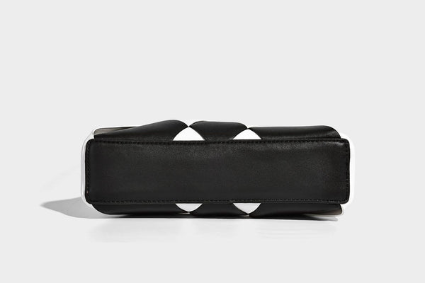 Compact bucket shoulder bag with black-and-white diamond patchwork panels, knotted top handle, gold-tone hardware, and