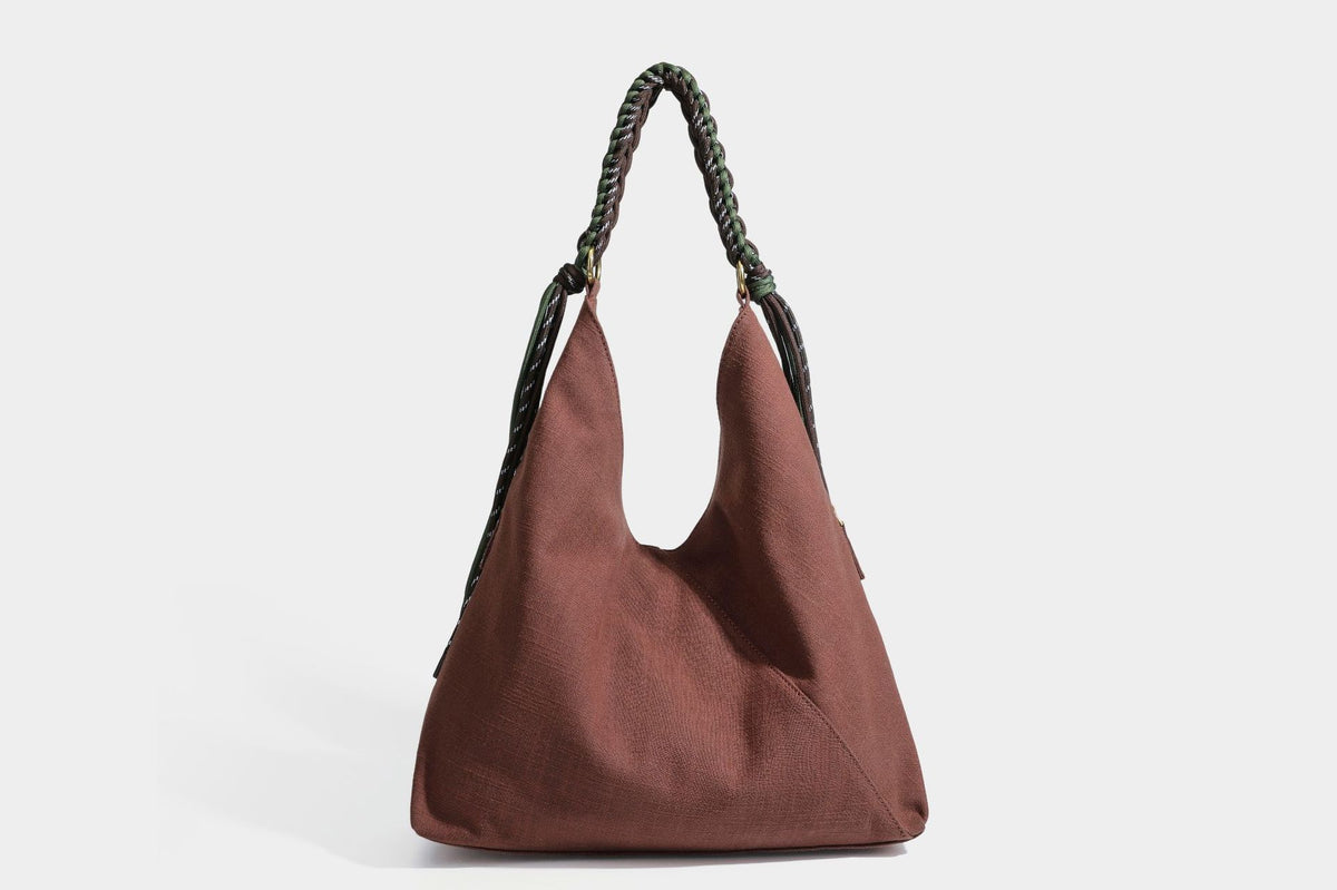 Soft slouchy cream canvas shoulder tote with braided brown and green cord handle, gold-tone ring hardware, and tassel trim