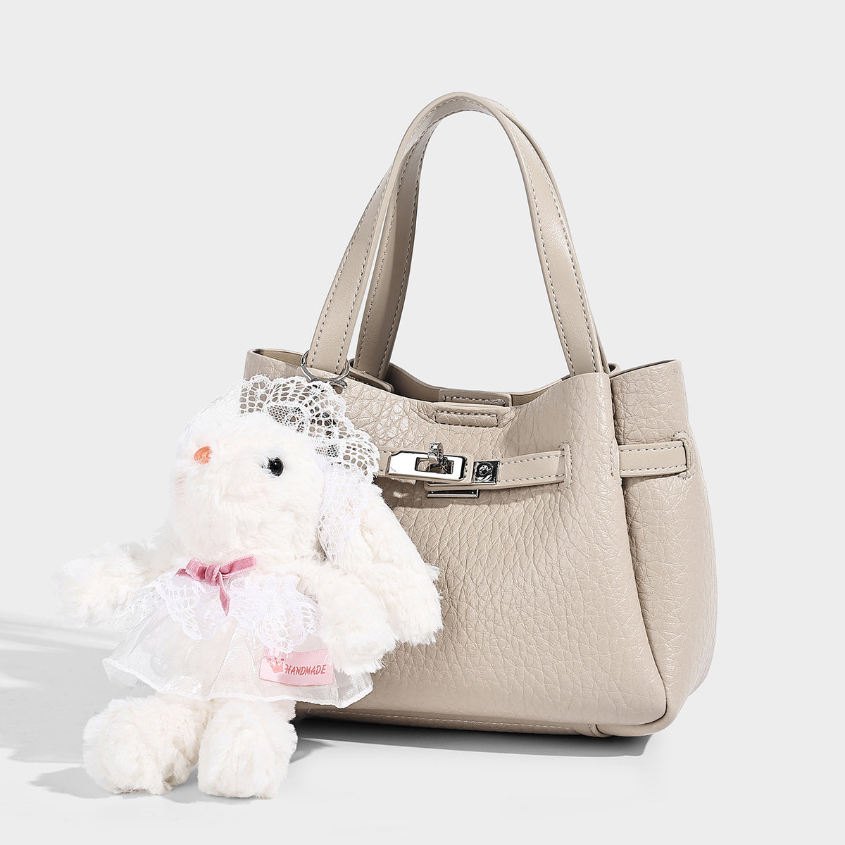 Small structured pebbled bucket tote with double top handles, silver turn-lock hardware, and detachable shoulder strap, front