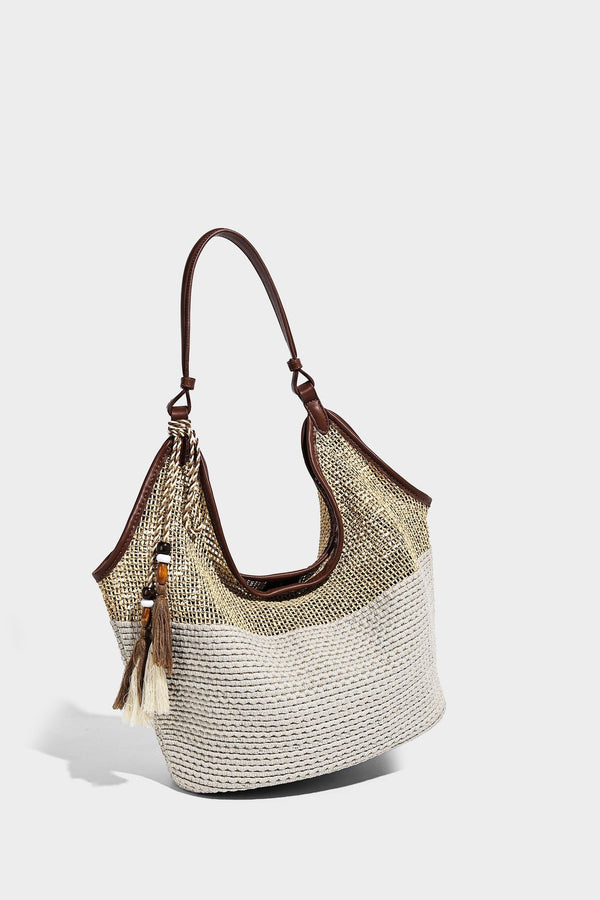Two-tone beige and cream woven straw hobo shoulder bag with brown leather-look trim, long shoulder strap, and tassel-bead