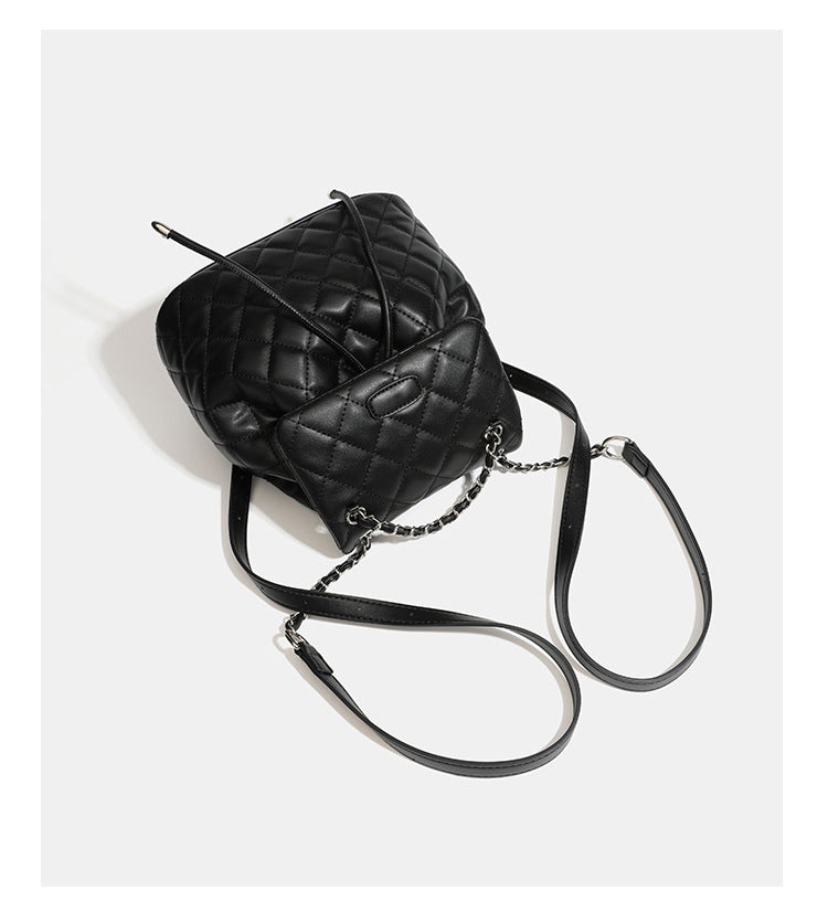 Black diamond-quilted backpack handbag with silver-tone chain flap accent and adjustable shoulder straps, detail view 15