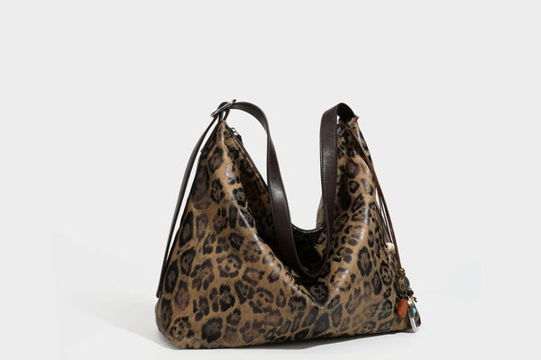 Slouchy leopard print hobo shoulder bag with glossy coated finish, top zipper closure, dark brown trim, and dangling charm