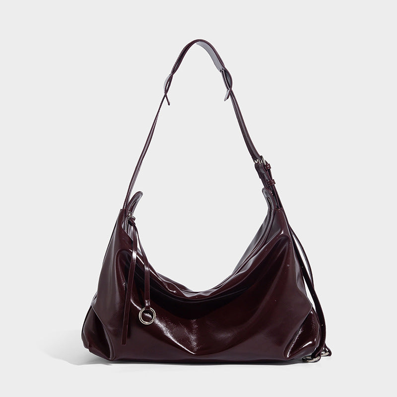 Glossy black slouchy hobo shoulder bag with zip closure, silver-tone ring hardware, and adjustable crossbody strap, detail