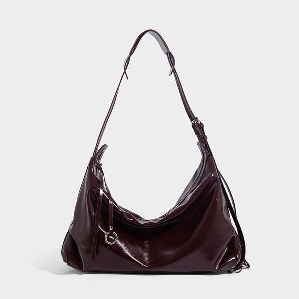 Glossy black slouchy hobo shoulder bag with zip closure, silver-tone ring hardware, and adjustable crossbody strap, detail