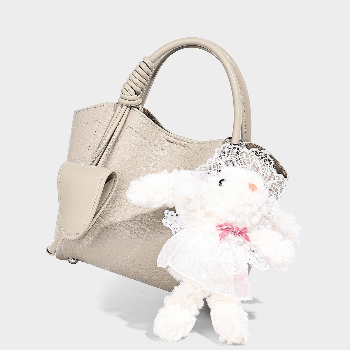 Structured mini tote bag in pebbled leather-look finish with knotted top handles, front flap pocket, and detachable shoulder