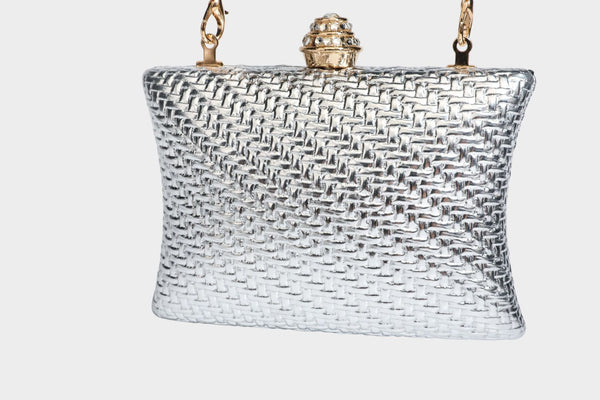 Small structured rectangular metallic woven-texture clutch bag with jeweled knob clasp and gold-tone chain strap, detail view