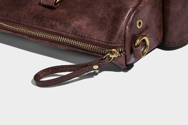 Distressed leather-look vintage satchel shoulder bag with multiple front zip pockets, dual top handles, and brass-tone